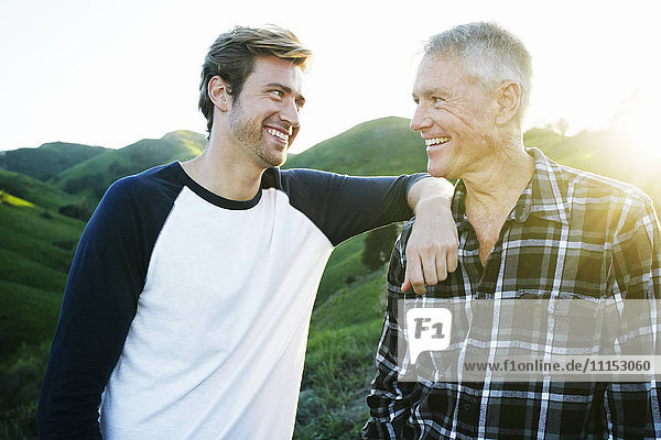 Kaukasischer Vater und Sohn lächelnd auf einer ländlichen Hügelkuppe