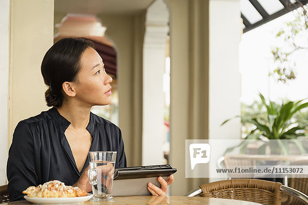 Asiatische Geschäftsfrau benutzt digitales Tablet in einem Café