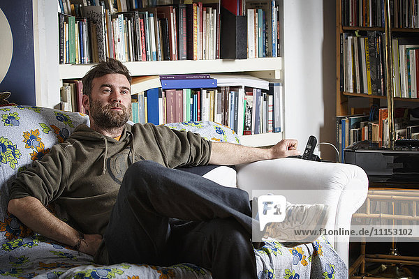 Kaukasischer Mann sitzt auf dem Sofa im Wohnzimmer