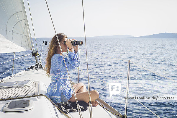 Kaukasische Frau mit Fernglas auf dem Bootsdeck