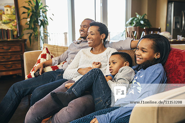 Schwarze Familie beim Fernsehen auf dem Sofa
