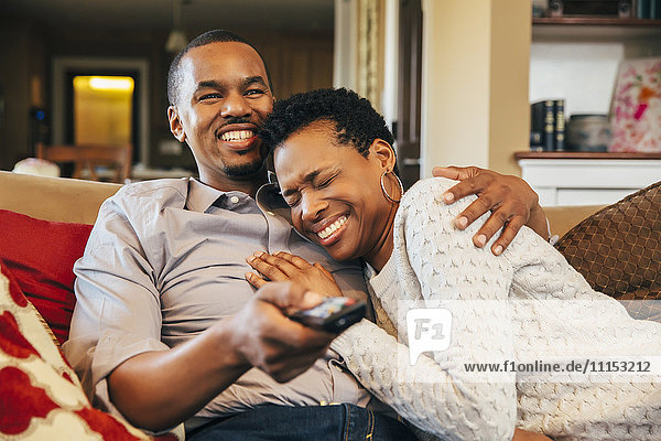 Black couple watching television on sofa