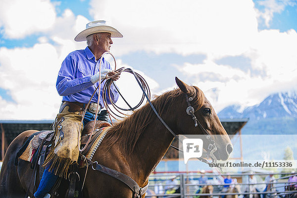 Älterer kaukasischer Cowboy reitet Pferd beim Rodeo