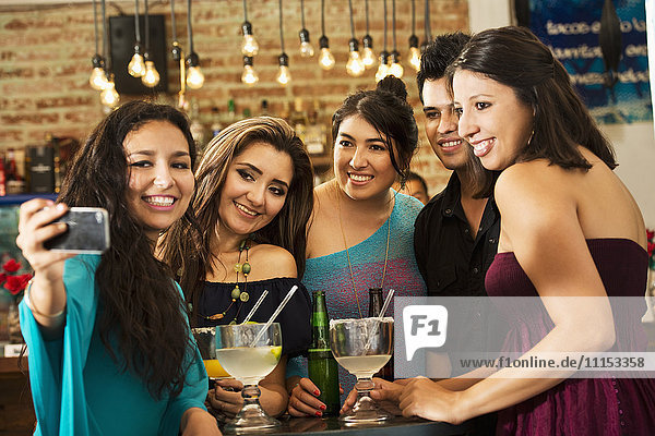 Hispanische Freunde machen ein Selfie in einer Bar