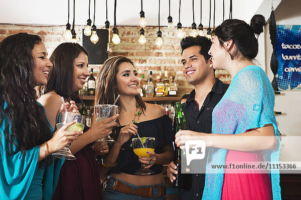 Hispanic friends having drink in bar