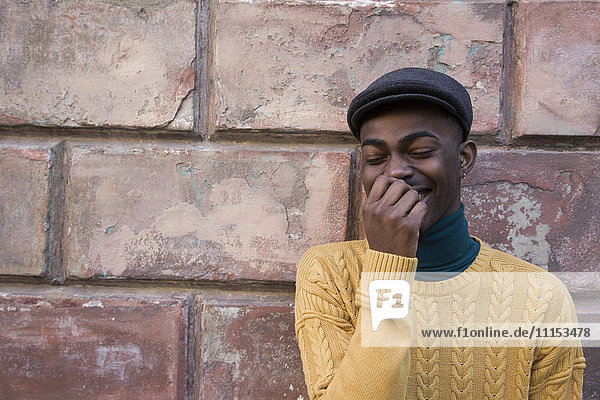 Black man laughing near brick wall
