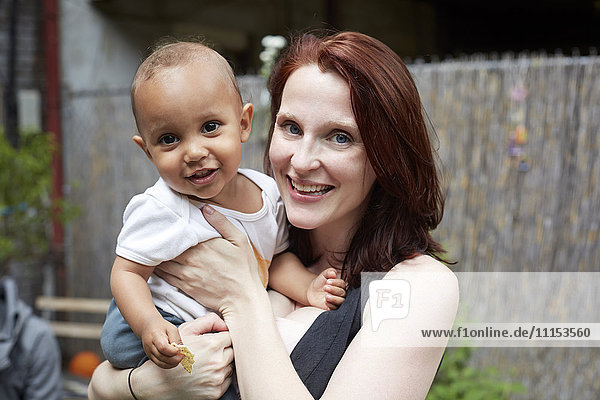 Lächelnde Mutter hält ihren kleinen Sohn im Hinterhof