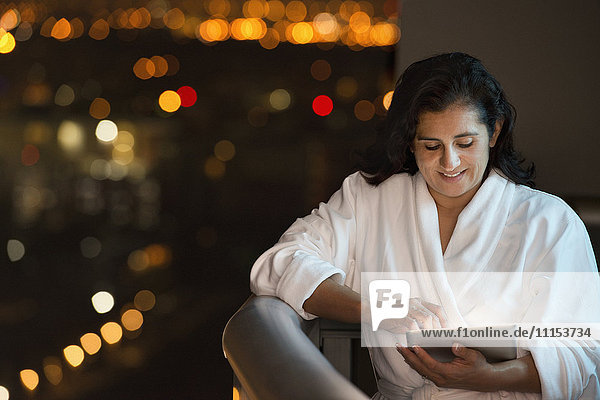 Hispanische Frau benutzt digitales Tablet auf dem Hotelbalkon
