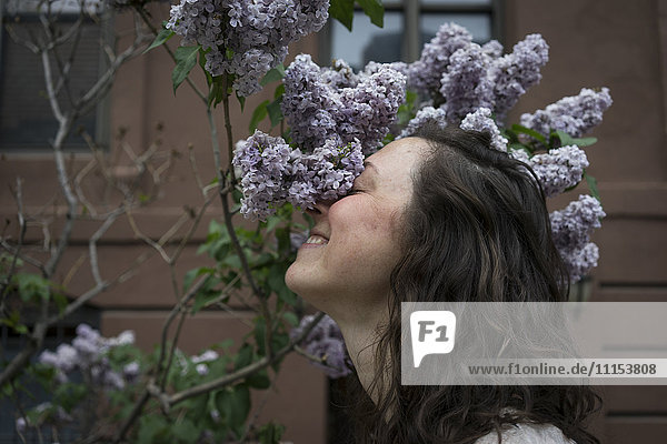 Kaukasische Frau riecht an Blumen auf einer Straße in der Stadt