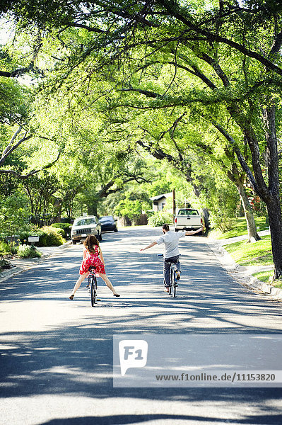 Caucasian children riding bicycles on suburban neighborhood street