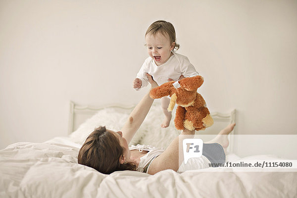 Kaukasische Mutter spielt mit Baby auf dem Bett