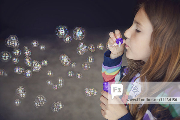 Kaukasisches Mädchen beim Blasen von Seifenblasen