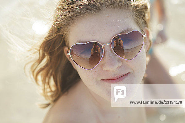Caucasian teenage girl wearing heart-shaped sunglasses