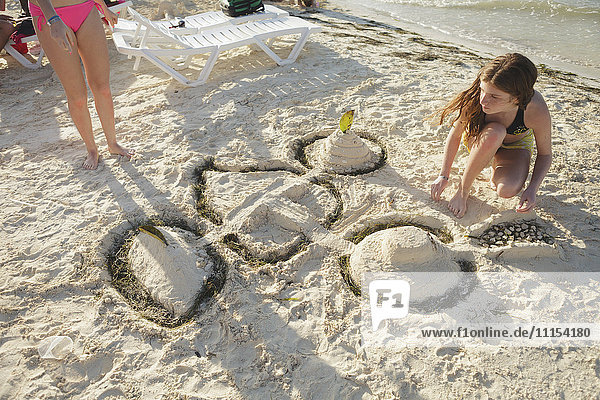 Kaukasisches Teenager-Mädchen baut eine Sandburg am Strand