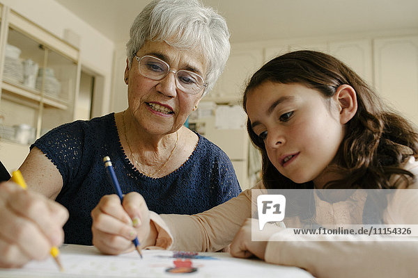 Grandmother and granddaughter drawing at table