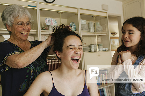 Großmutter frisiert die Haare ihrer Enkelin im Esszimmer