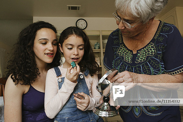 Großmutter hilft Enkeltöchtern beim Auftragen von Lippenstift im Spiegel