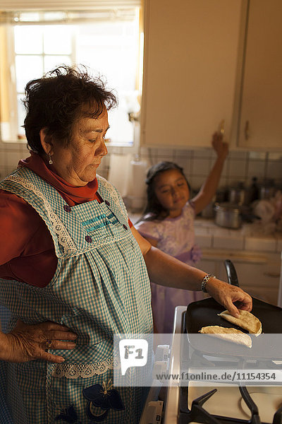 Hispanische Frau kocht für ihre Enkelin in der Küche