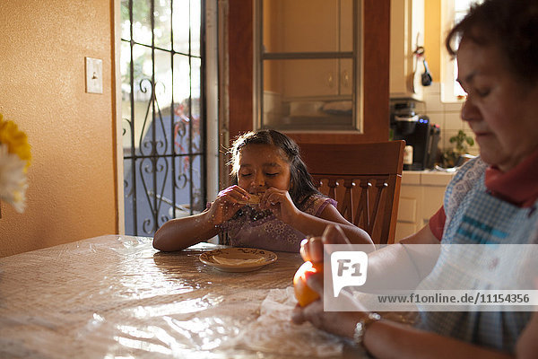 Hispanische Großmutter und Enkelin essen in der Küche