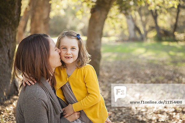Mutter küsst Tochter im Park