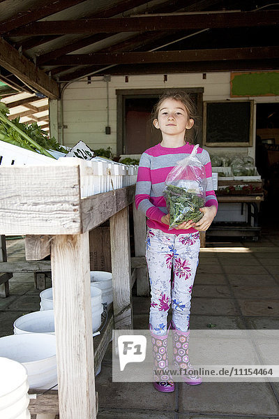 Ein gemischtrassiges Mädchen hält eine Tüte mit Produkten auf dem Bauernmarkt