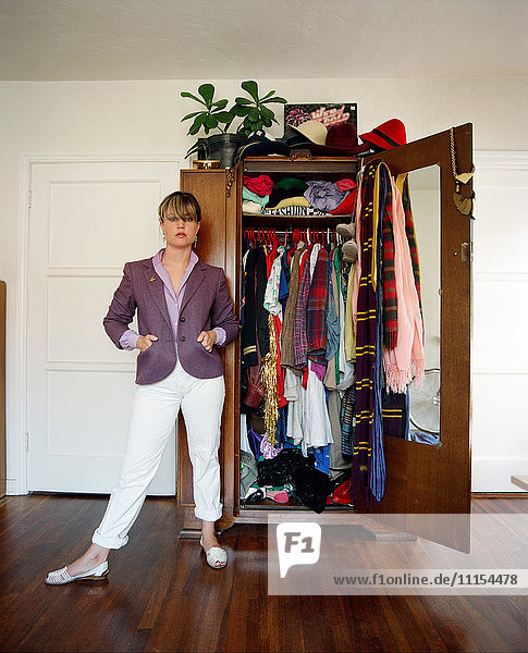 Stilvolle Frau steht in der Nähe von Kleiderschrank