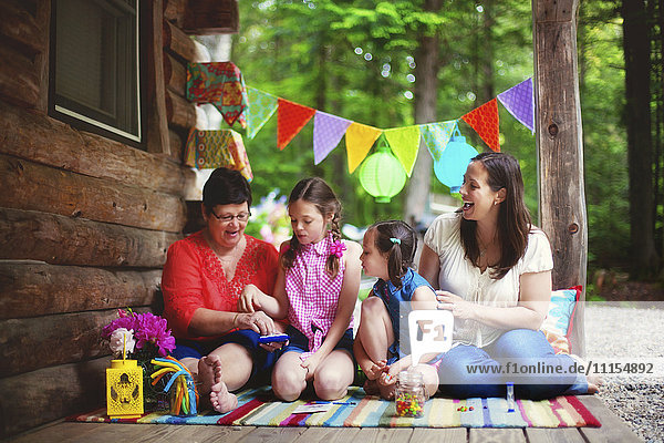 Three generations of Caucasian women playing with toy on cabin porch