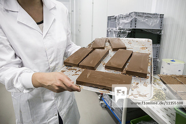 Frau hält ein Tablett mit Schokoladennougat in einer Schokoladenfabrik