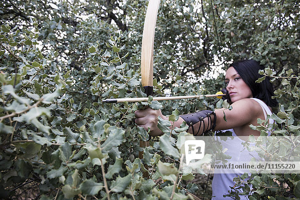 Archeress aiming with a bow in a forest