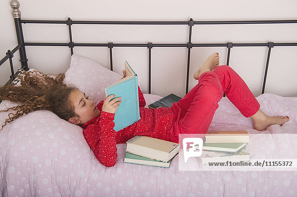Kaukasisches Mädchen liest Bücher auf dem Bett