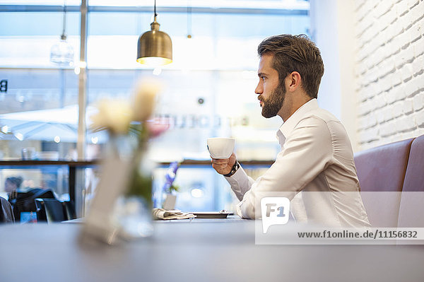 Geschäftsmann sitzend in einem Café mit Tasse Kaffee