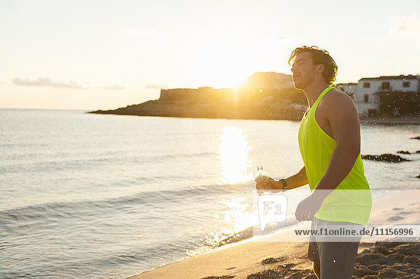 Spanien  Mallorca  Jogger mit Wasserflasche am Strand