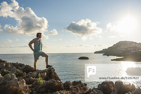 Spain  Mallorca  Sportsman standing on rocky coast in the morning