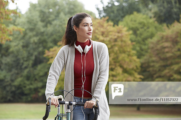 Woman with headphones and bicycle in an autumnal park