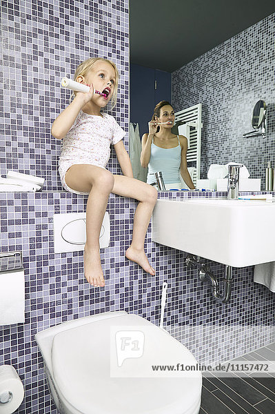 Mutter und Tochter beim Zähneputzen im Bad