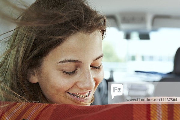 Lächelndes Teenagermädchen mit Zahnspange im Auto