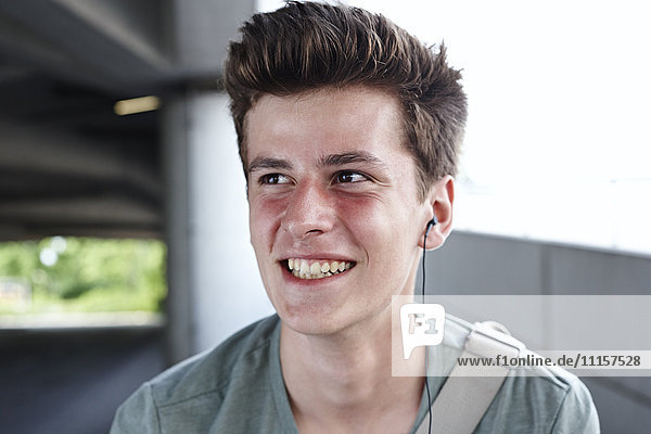 Lächelnder Teenager mit Ohrstöpseln im Freien