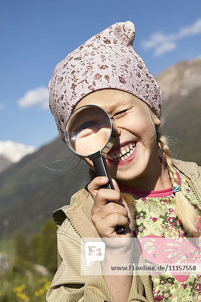 Happy girl looking through magnifying glass