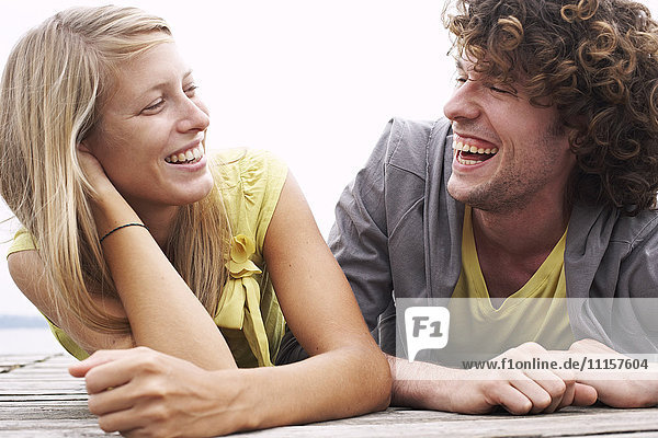 Lachendes junges Paar auf einem Steg liegend