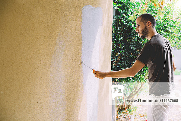Man painting wall with paint roller