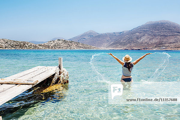 Griechenland  Kykladeninseln  Amorgos  Frau  die im blauen Wasser der Ägäis neben einem Holzsteg plätschert