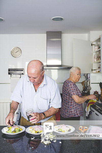 Seniorenpaar bei der Zubereitung von Speisen in der Küche