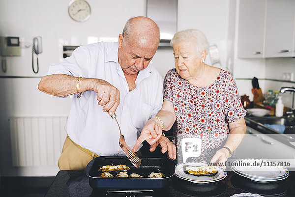 Seniorenpaar serviert gefüllte Auberginen in der Küche