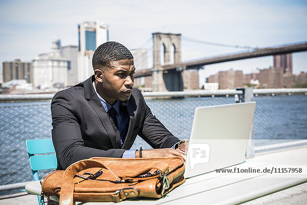 USA  Brooklyn  businessman working with laptop outdoors