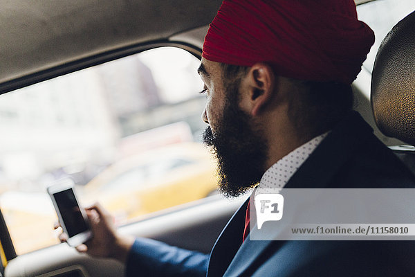 Indian businessman using smartphone in taxi