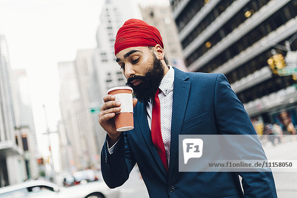 Indischer Geschäftsmann  der in Manhattan spazieren geht und Kaffee trinkt.