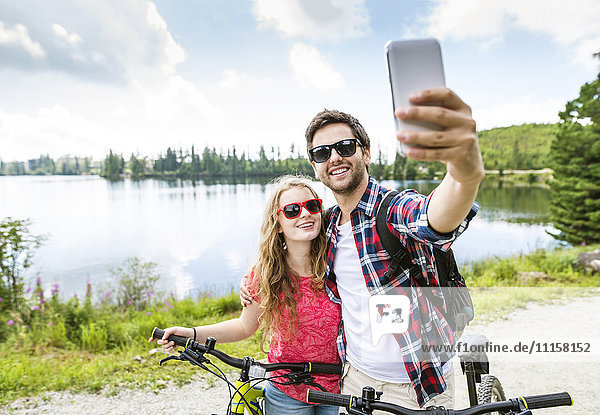 Young couple taking selfies on a bicycle trip