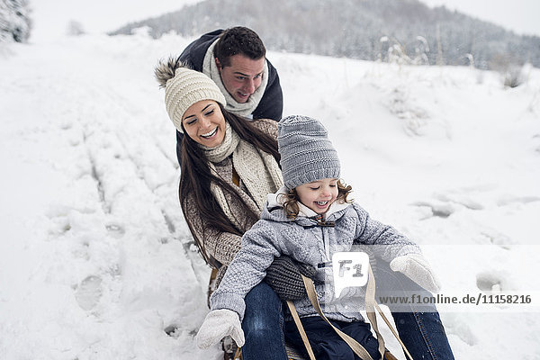 Glückliche Familie auf Schlitten in der Winterlandschaft