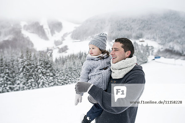 Father holding daughter in winter landscape