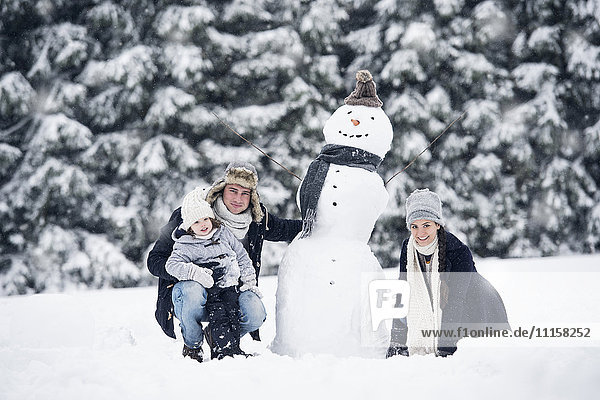 Familie posiert am Schneemann